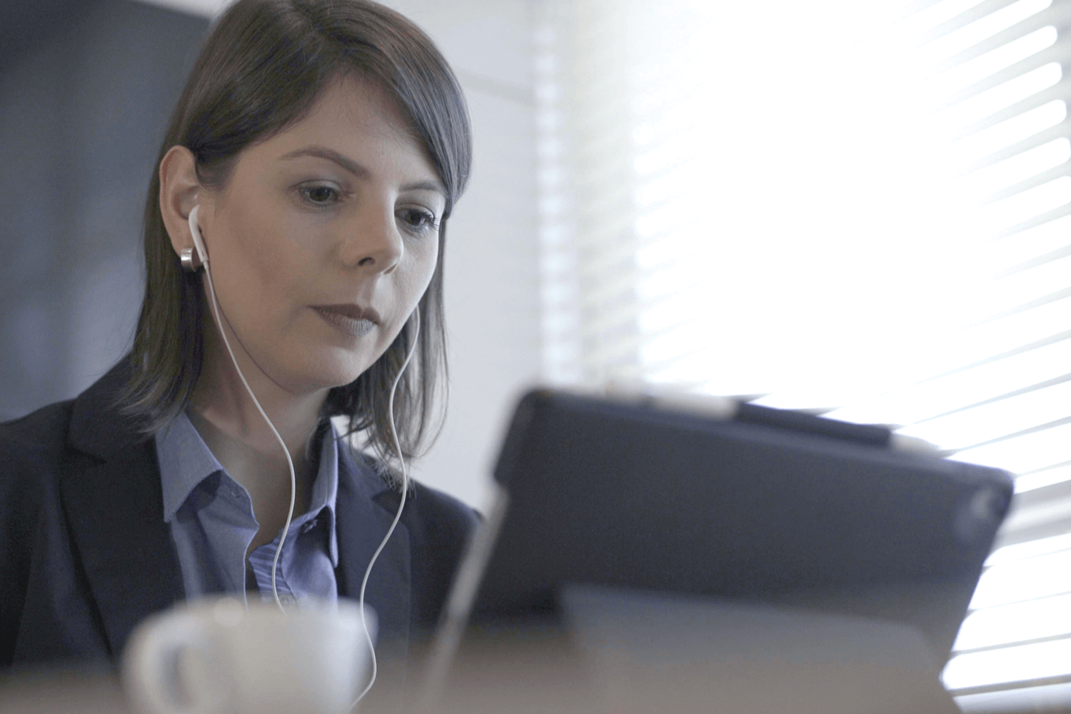 mulher sentada, com fone de ouvido, usando laptop